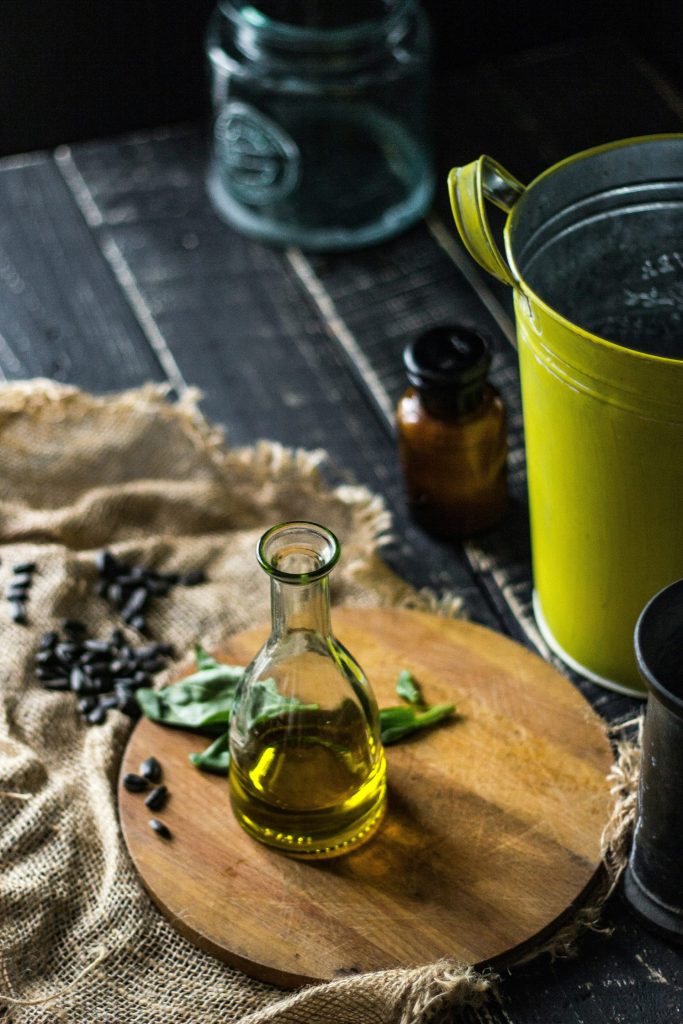 clear glass bottle beside green ceramic mug